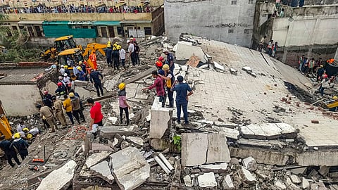Officials and others during a rescue operation after a building collapse, in Surat district, Saturday, July 6.
