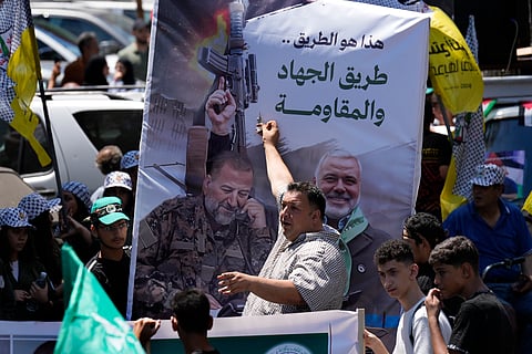 A Hamas supporter shouts slogans in front of a poster that shows Hamas political chief Ismail Haniyeh, right, who was killed in an assassination in Tehran, and of the late Hamas commander Saleh Arouri, during a symbolic funeral in Beirut, Lebanon, Friday, Aug. 2, 2024. The Arabic words on the poster read:" This is the road of the resistance and jihad".