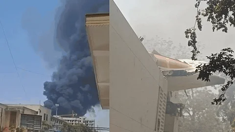 Heavy black smoke was seen rising from the crash site near Forensic Cross Road. Visuals from local crews show extensive wreckage and fire. Firefighters and rescue personnel are on site conducting evacuation and containment.
