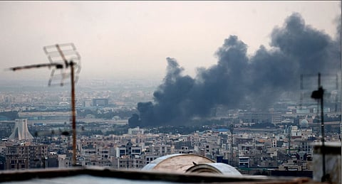 Smoke billows from an explosion near the Azadi Tower (L) in Tehran on June 16, 2025. 