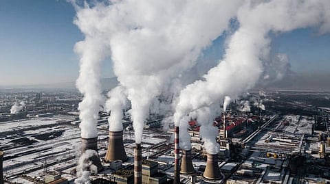 Factory chimneys releasing thick smoke into the sky, showing industrial air pollution