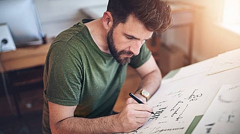 Man focused on writing notes or diagrams on a large sheet of paper.