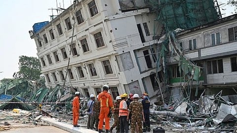Rescue workers standing near a partially collapsed building.