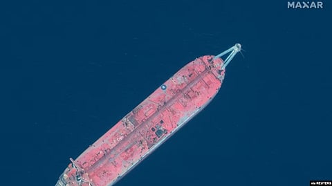 An aerial view of a large red cargo ship floating in deep blue water.