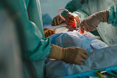 Surgeons performing an operation in a sterile environment under bright surgical lights.