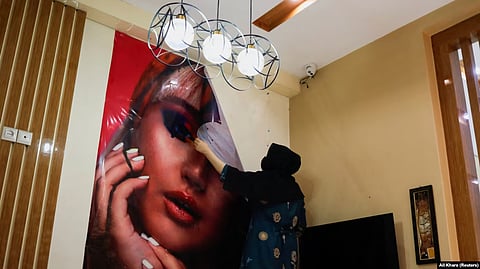 AFGHANISTAN -- An Afghan beautician removes a poster in a beauty salon in Kabul, Afghanistan, July 24, 2023.