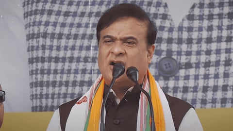 In the image chief minister himanta biswa is giving a speech there are mikes and he is telling something to the people he is addressing