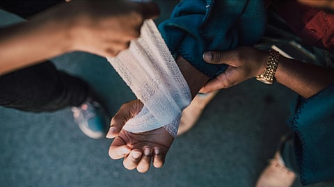 In the image someone is shown dressing the wound of someone 