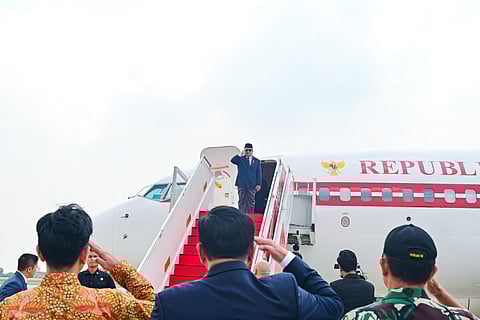 In the image the president is shown standing on the plane door saluting the people standing down from above.