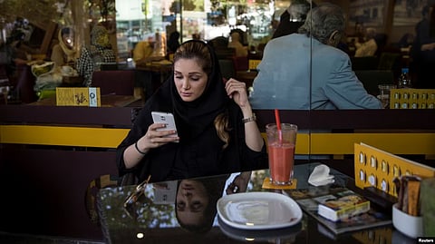 In the image a women is shown in the café looking at her phone