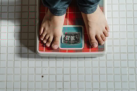 A man checking his weight on the weighing scale.