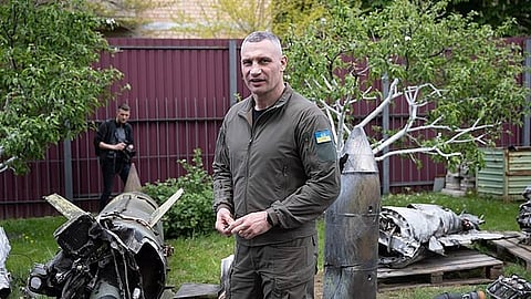 ukrainian soldier standing besides damaged russian drones.
