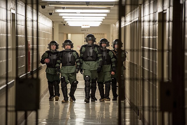 An ERO SRT team walks through a detention facility in riot gear