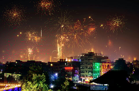 Image of firecrackers in the sky with a lot of buildings covered in lights showcasing the Diwali environment in India