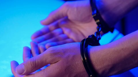 image of a man wearing hand cuffs in dim blue light aesthetic