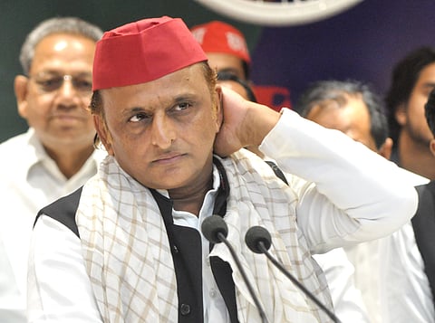 SP chief Akhilesh Yadav wearing black non sleave coat white kurta and red cap adressing the people