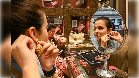 A woman admires her earrings while looking at her reflection in a mirror.