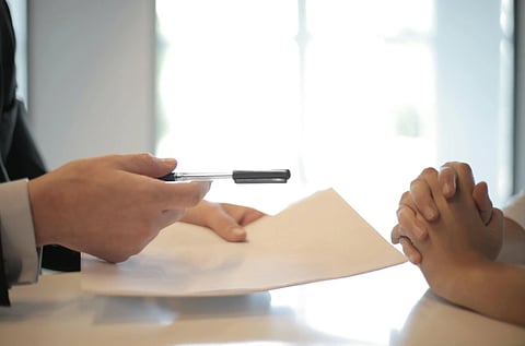 Image of a lawyer handing over documents and pen to his client. the background of the image is bright.