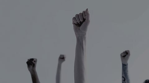 In the image peoples are shown raising their hands indicating protest