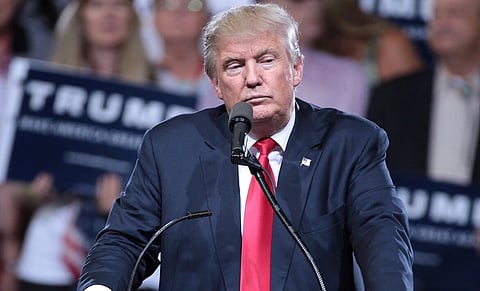 Image of Trump giving a speech wearing his blue suit and red tie. he has got frown on his face and he is looking down. he is with supporters at a campaign rally at Veterans Memorial Coliseum at the Arizona State Fairgrounds in Phoenix, Arizona.
