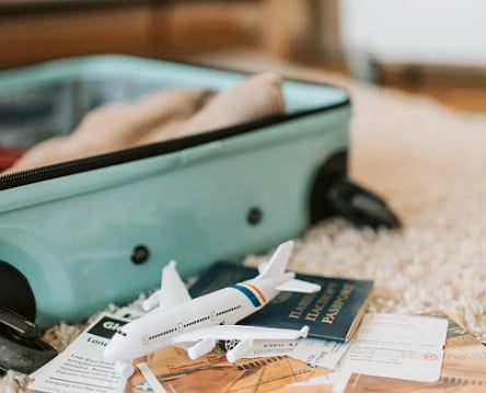 Image of packing the suitcase along with plane tickets and and tiny toy of aeroplane