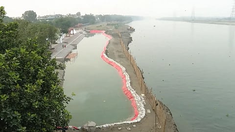 A screenshot from Saurabh Bharadwaj's livestream, showing the 'fake ghat' filled with filter water, and the actual polluted Yamuna next to it.