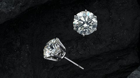 In the image two diamonds are shown in earing with black background
