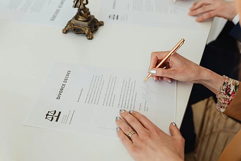 Person signing a divorce decree with a gold pen.