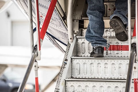 An illegal immigrant boards a plane for a removal flight while wearing shackles on their feet.