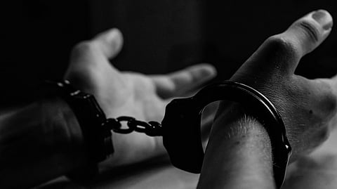 In the image a person is shown trapped in handcuffs for a crime