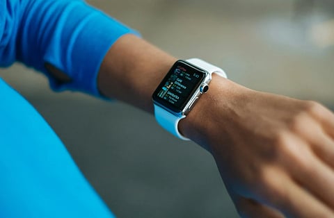Image of woman wearing Apple watch on her wrist, checking her health statistics. 