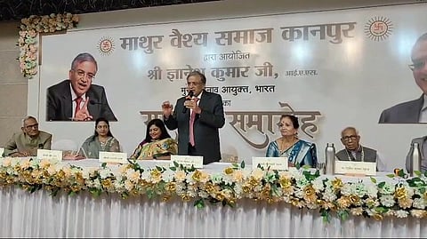 In the image election commission employees are shown siting in the panel and Chief Election Commissioner Gyanesh Kumar is addressing the audience