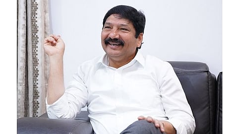 YSRCP leader and former Minister Jogi Ramesh sitting on a sofa wearing a white shirt, smiling.