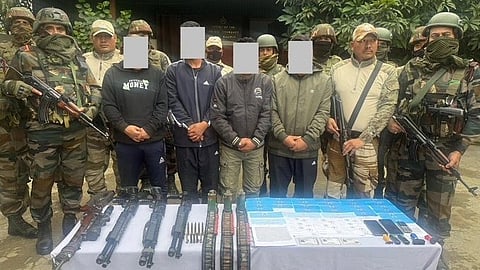 Security forces with the arrested militants and seized weapons posing for an image. The security personnel are in their uniform and gun with them