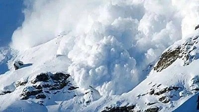 Snow-covered Himalayan mountain slope with rescuers making their way through avalanche debris near Yalung Ri in Dolakha district, Nepal.