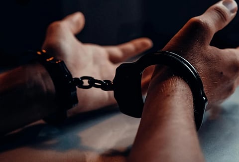 Image of a man wearing black handcuffs as he is in custody