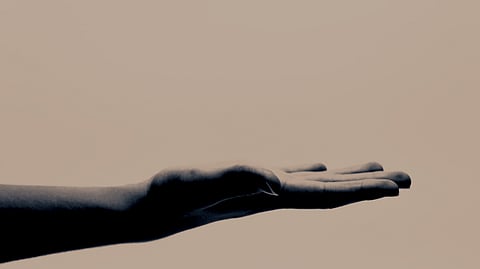 In the image someone's hand is shown askinng for something 