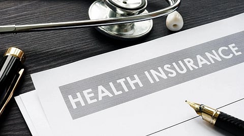 Image of a paper with the text Health Insurance on it. The picture also includes a stethoscope, and a pen