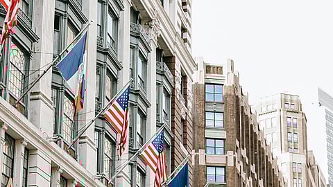 In the image NYC is shown with many USA Flags tied in it buildings