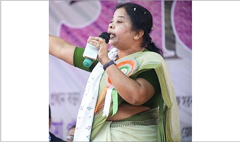 In the image TMC MLA Asima Patra is shown adressing the public form the stage wearing Saree