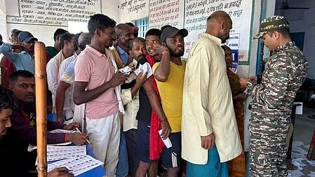 In the image Polling booth is shown and people are standing outside it in a cue