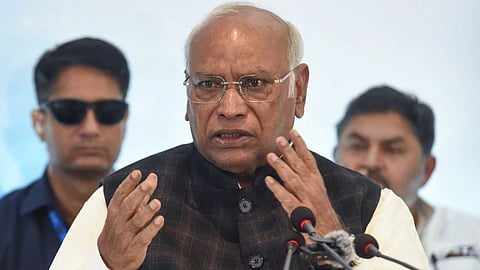 Congress Leadrer Mallikarjun Kharge addressing a rally in Bihar, wearing a white kurta and a Nehru jacket over it. He is speaking in the podium and his bodyguard can be seen in the background.