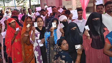 Polling officers and voters at a Bihar election booth, with EC staff monitoring turnout-related arrangements amid vote-slowing allegations.
