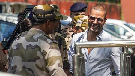 In the image Shikhar Dhawan is shown smiling with police officers