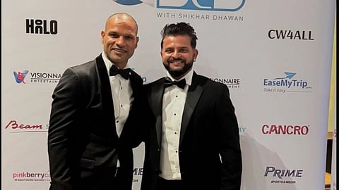 Cricketers Shikhar Dhawan and Suresh Raina dressed in black suit, posing for a picture together in an event. 