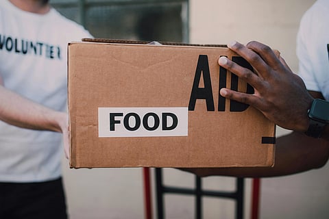 In the image volunteers are shown with food boxes in their hands