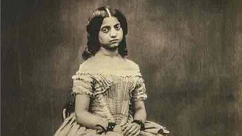 In the image a girl is shown wearing a Umbrella gown looking at the camera with dead eyes
