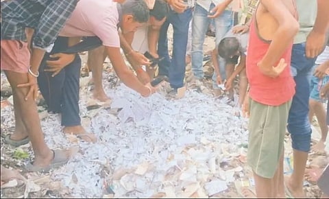 People gathered around a pile of VVPAT slips, inspecting them and taking photos.