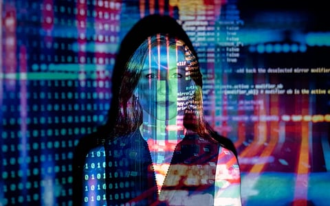 A person stands with colorful programming code projected over them, conveying technology's integration with human identity. The tone is futuristic and innovative.