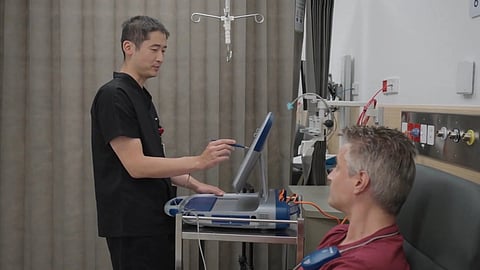 Laboratory view of a CRISPR-Cas9 gene-editing setup, a doctor is examining a patient is being seated and there are devices used to track. 